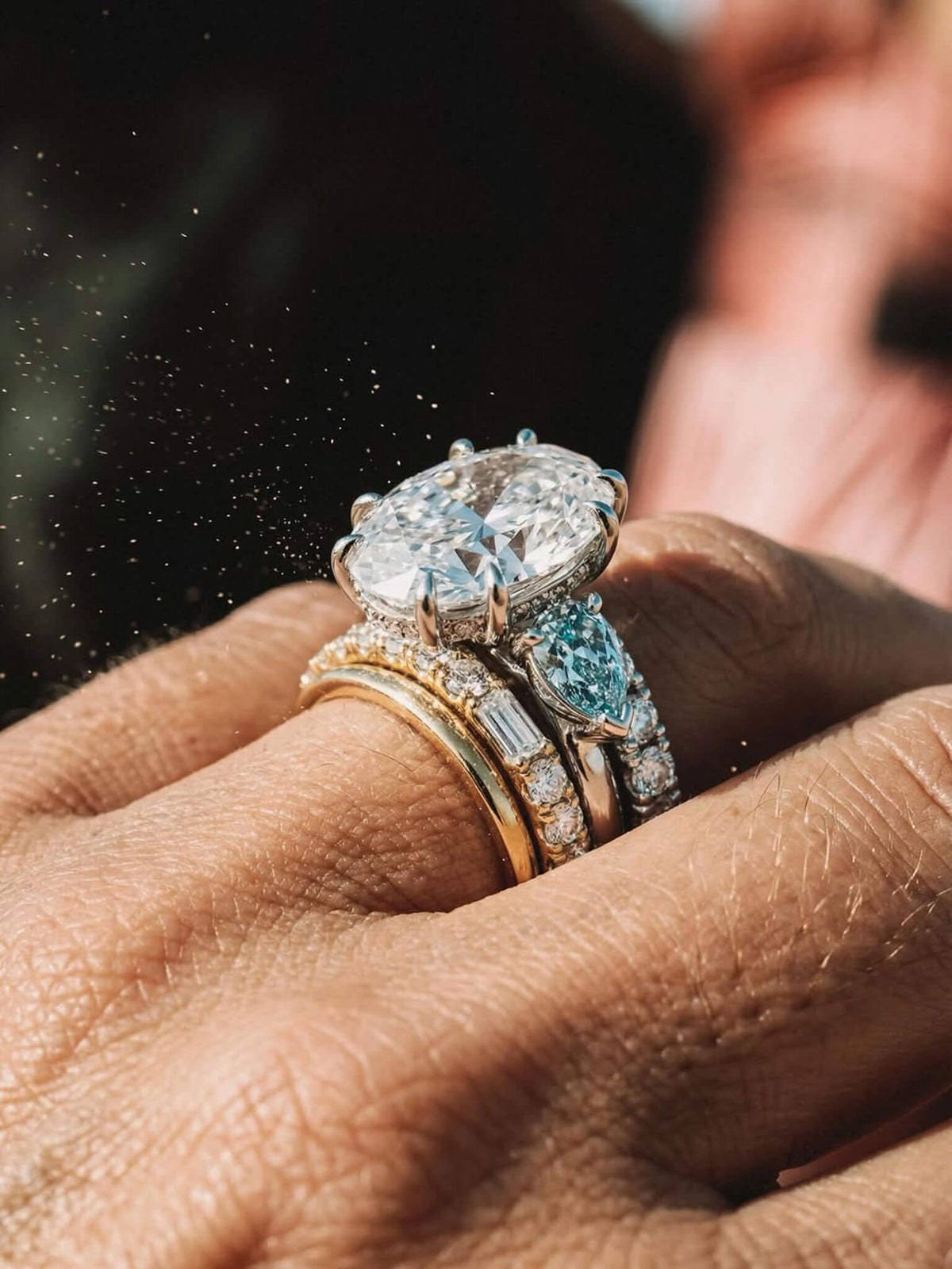 Stack of rings and a large diamond ring on a woman's finger.