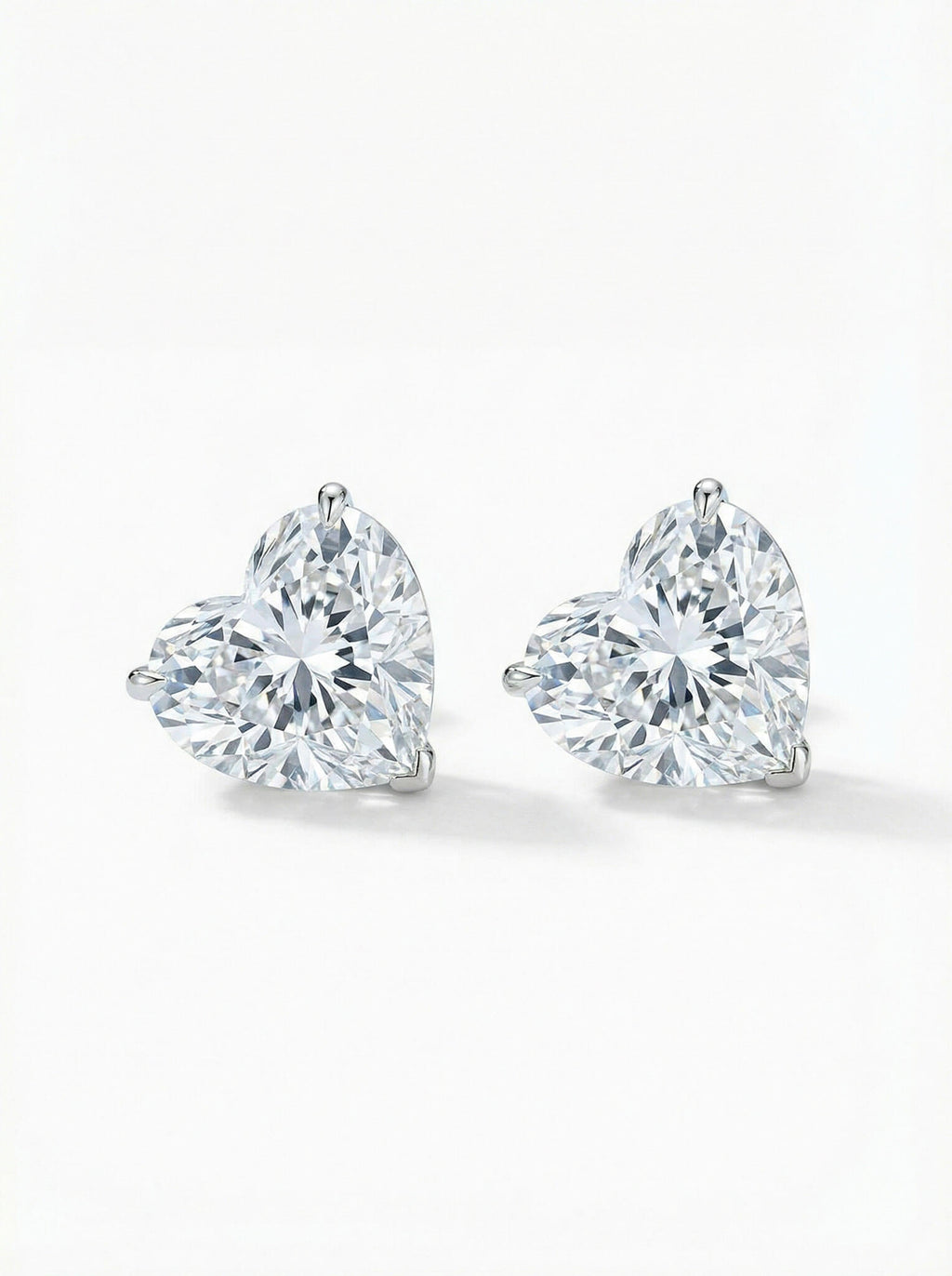 Pair of heart-shaped diamond stud earrings on a white background