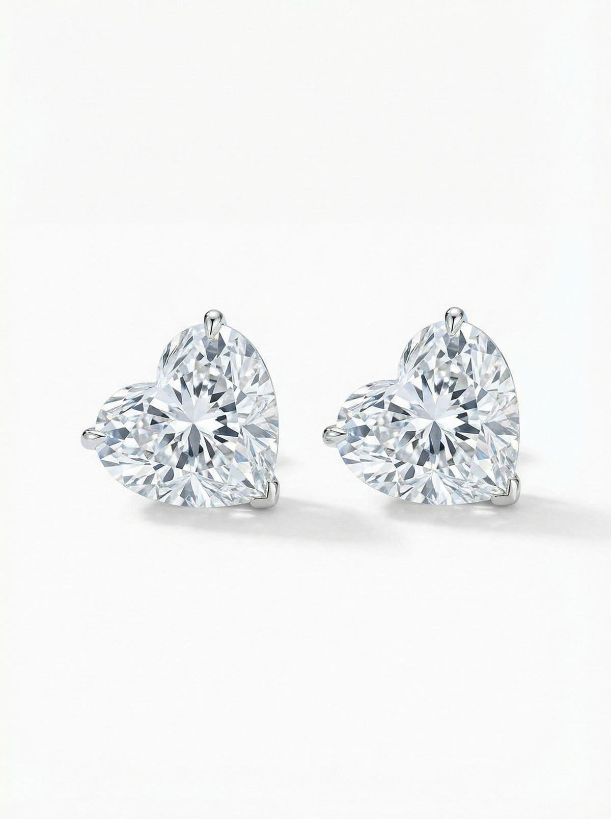 Pair of heart-shaped diamond stud earrings on a white background